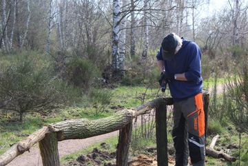 Ein Ehrenamtlicher des BUND Köln baut ein neues Geländer in der Dellbrücker Heide auf.