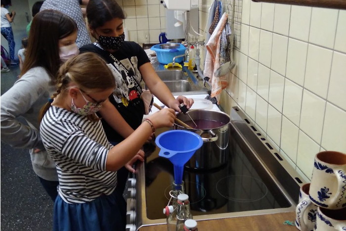 Der Traubensaft wird von Schülerinnen erhitzt und in Flaschen abgefüllt.